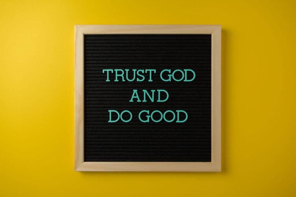 Inspirational message 'Trust God and Do Good' on a stylish black letter board with a vibrant yellow background.